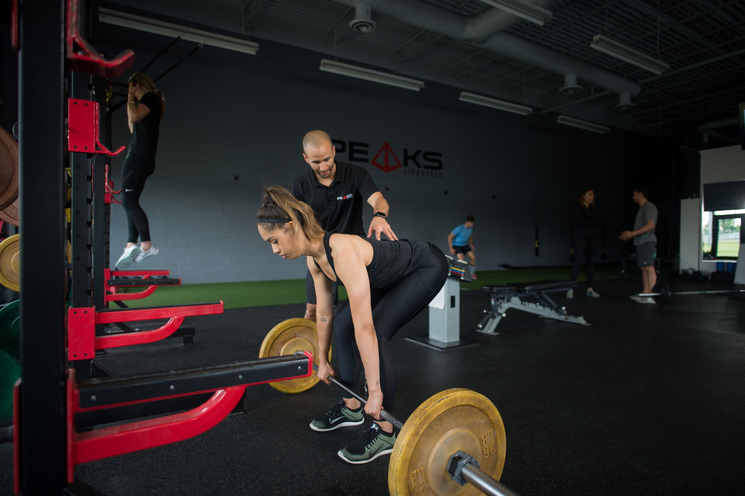 Adrian coaching a client through a barbell lift at Peaks